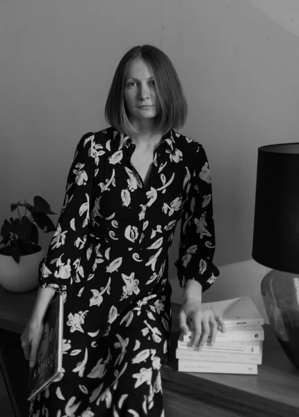 A co-founder of AVELaunch Books standing beside a stack of published books